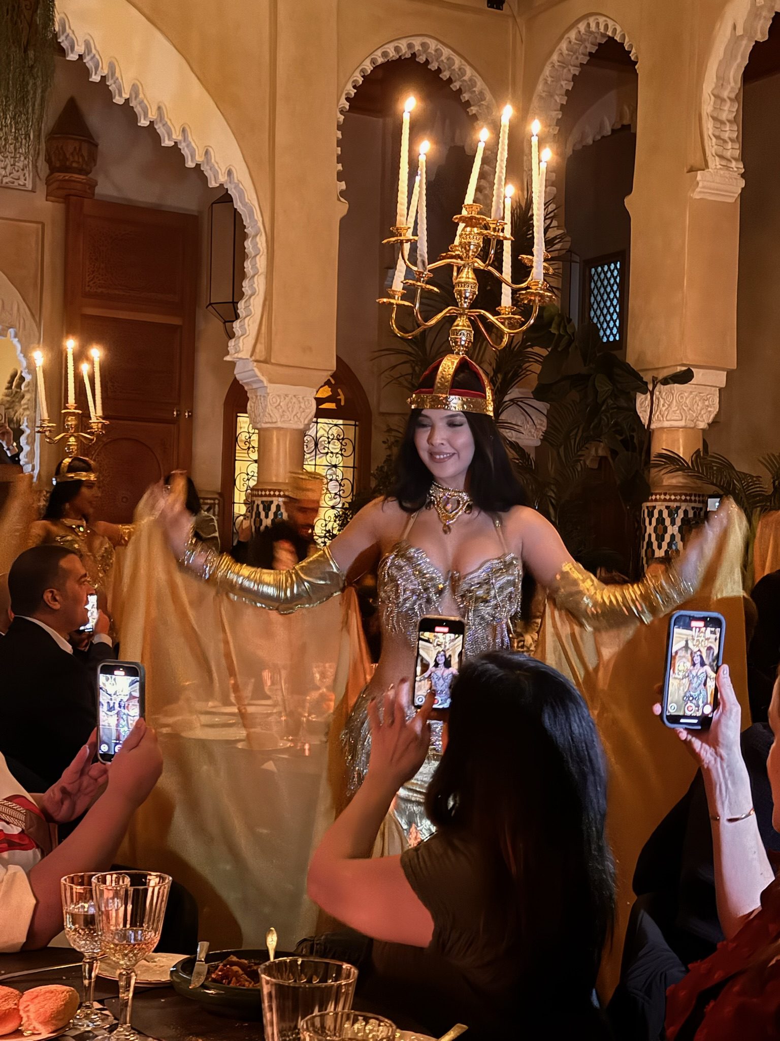 Belly dancer in a gold costume performing under candlelight at Dar Dada