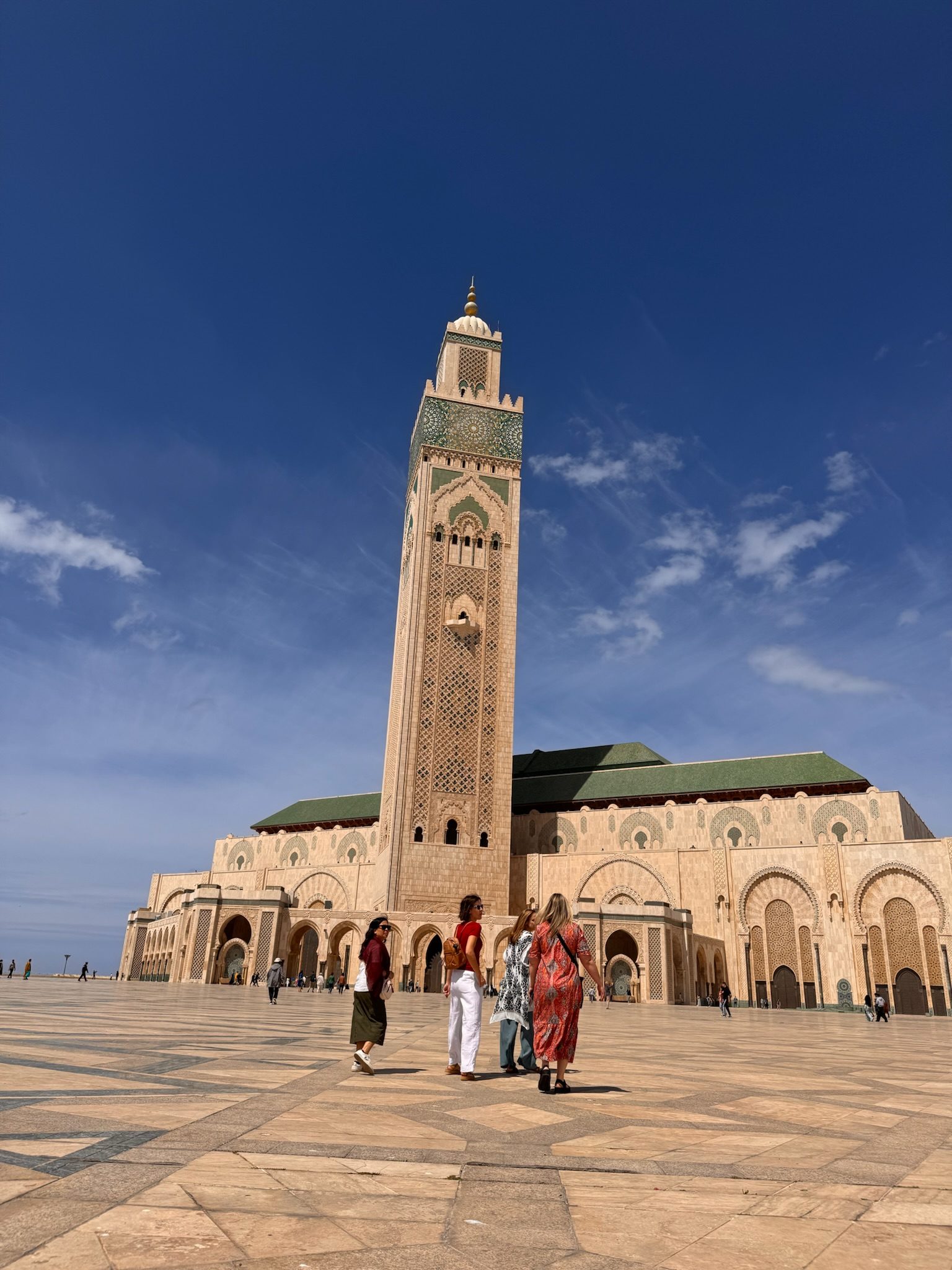 Women walking across the plaza in front of the Hassan II Mosque minaret