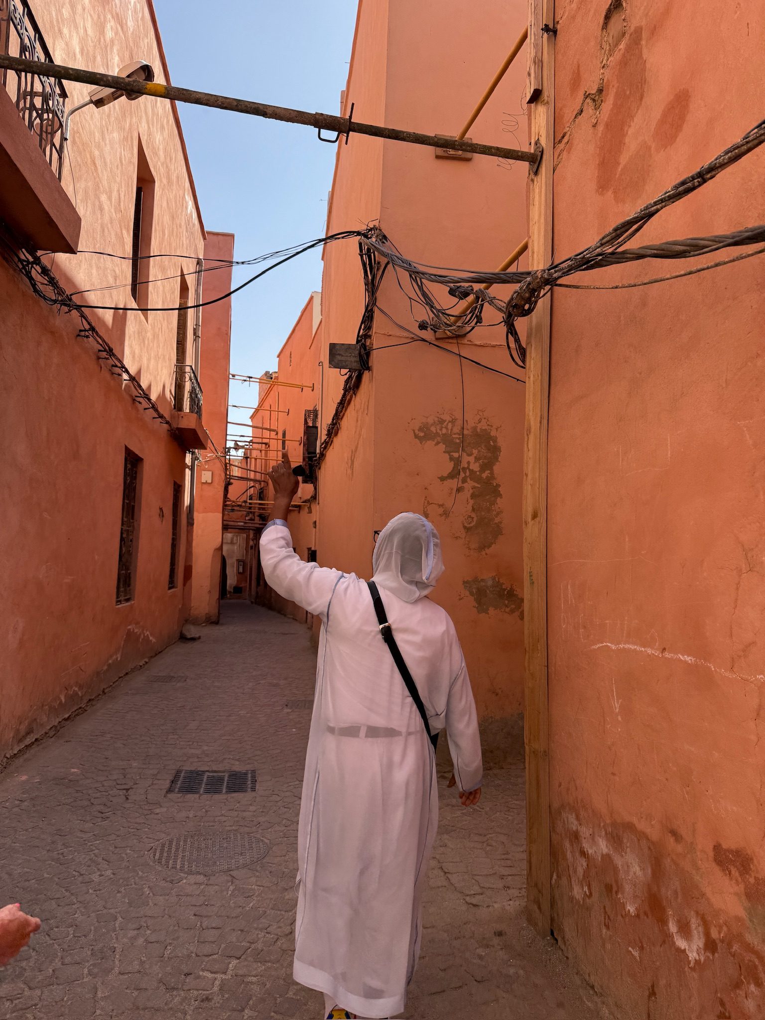 Woman walking down a narrow terracotta alley in the Marrakesh medina