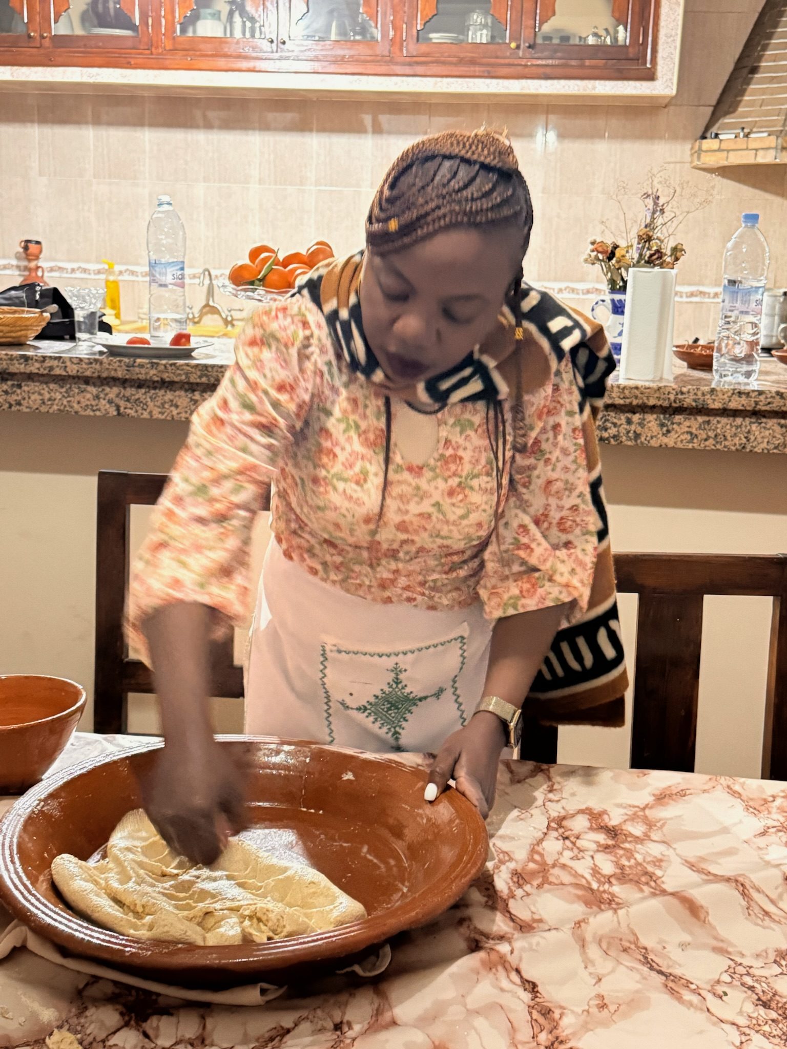 Woman kneading Moroccan bread dough in a clay bowl