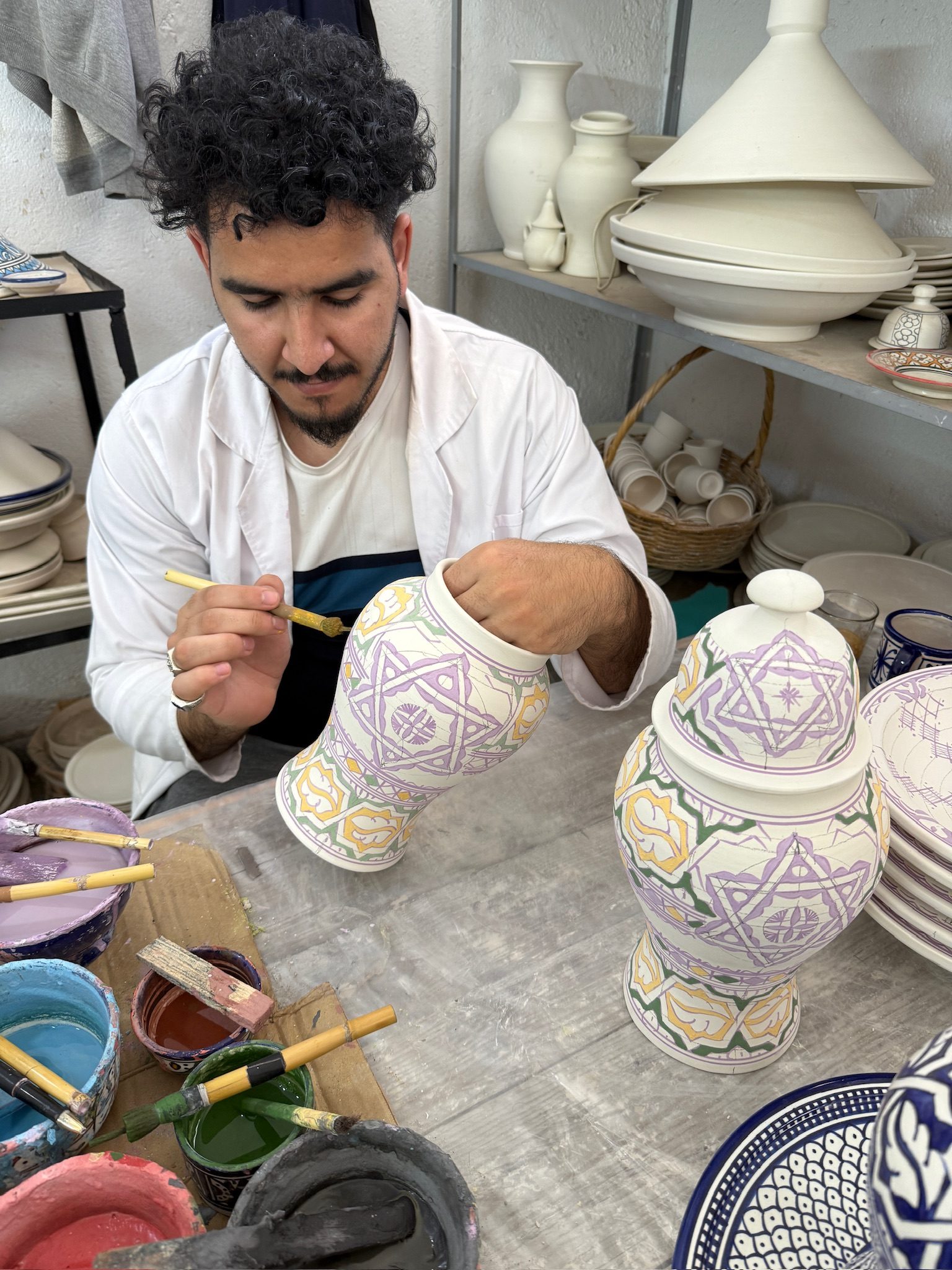 Artisan hand-painting a ceramic vase at a pottery workshop in Fes