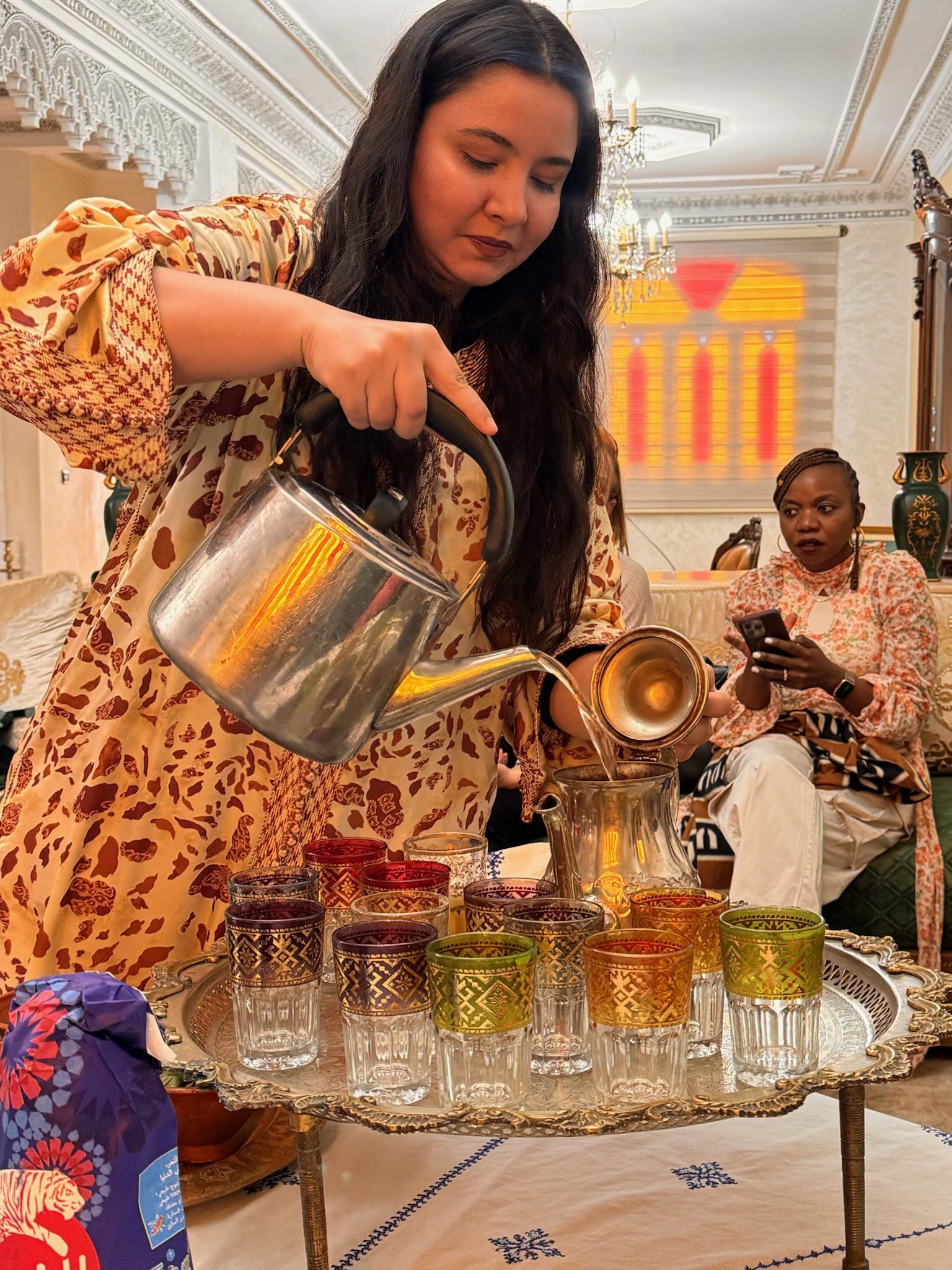 Woman pouring mint tea into colored glasses on a silver tray