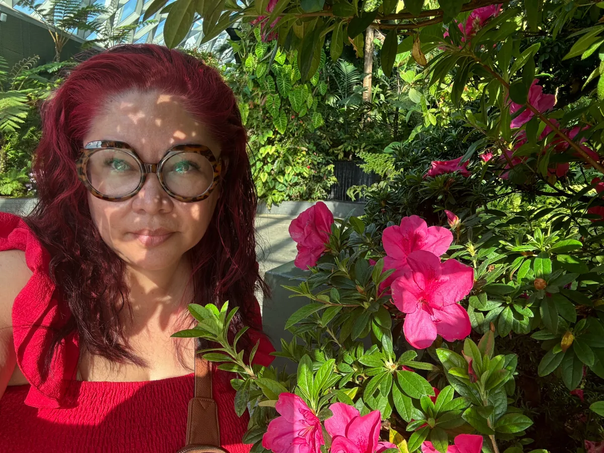 Cynthia smiling beside bright pink flowers in Singapore