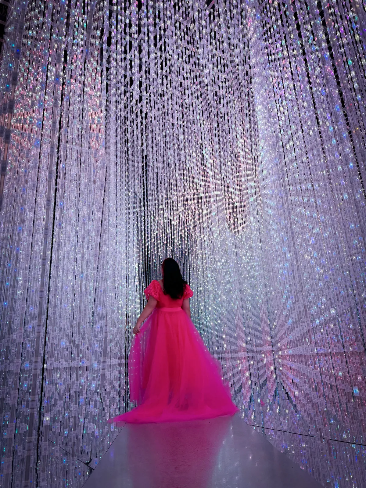 Cynthia in a flowing pink tulle dress inside the Crystal Universe light installation at teamLab Future World