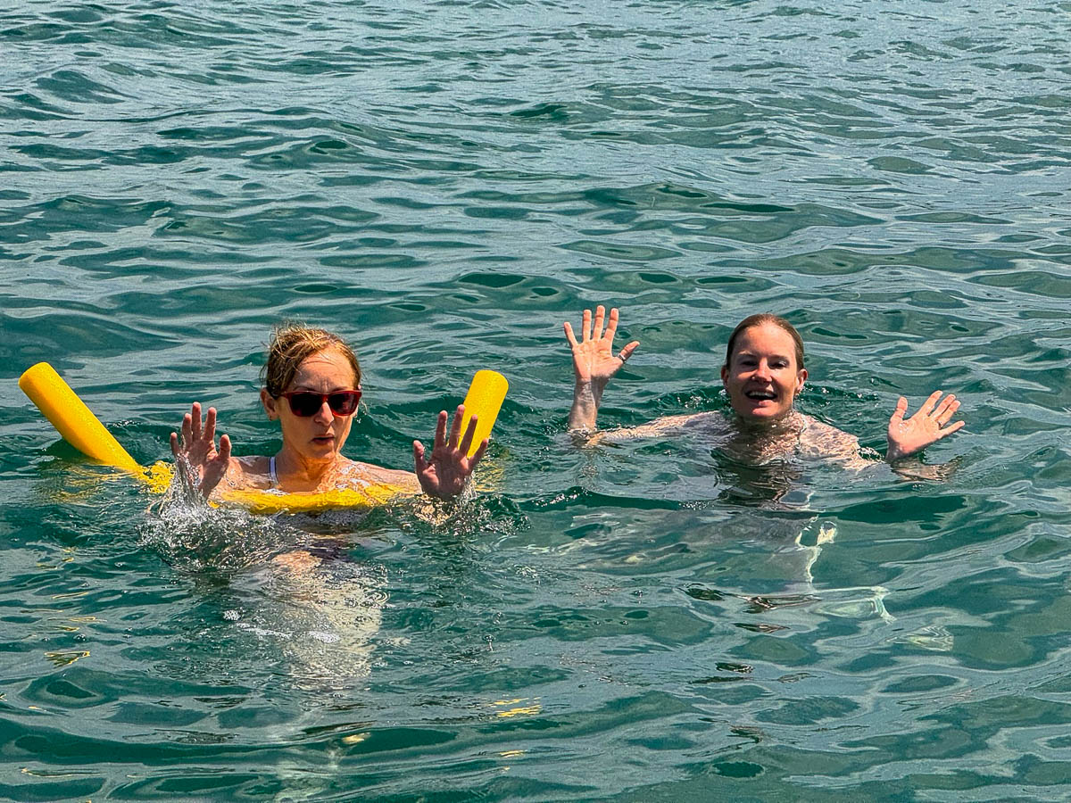 Two friends floating with pool noodles in the clear water of the Rosario Islands