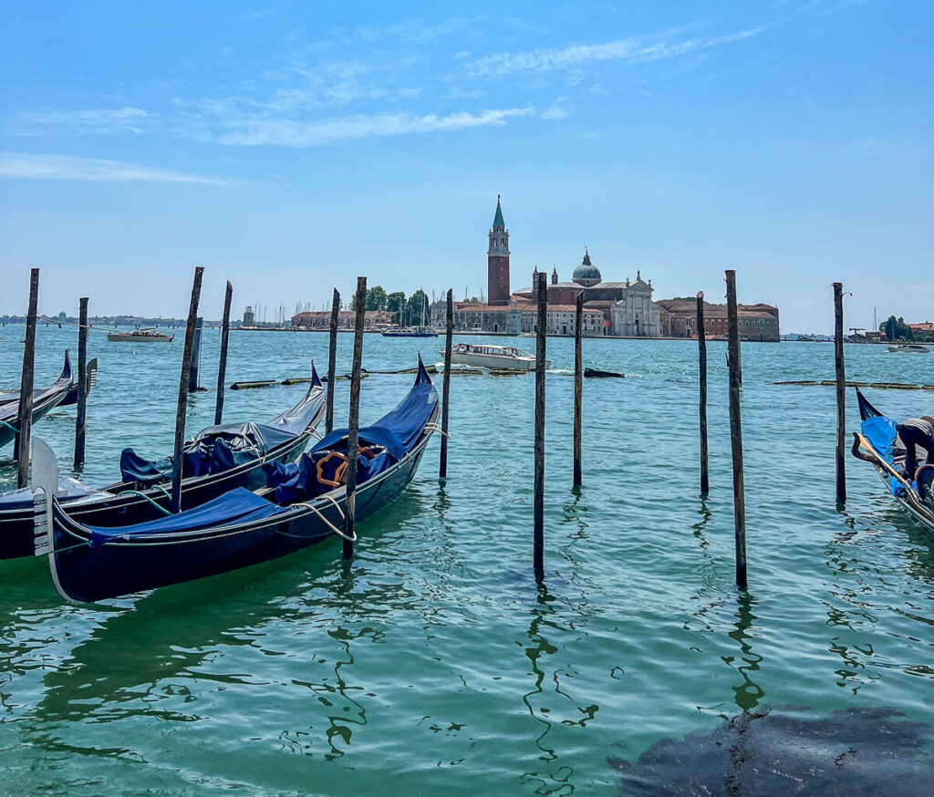 Gondolas moored along the Venice waterfront with the island church of San Giorgio Maggiore across the water.